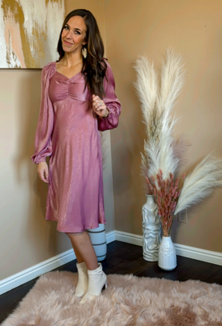 Woman in a pink dress standing in a room with decorative elements.