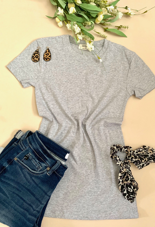 grey tee flatlay  with leopard accessories