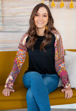 black boho top wiith jeans sitting on a sofa