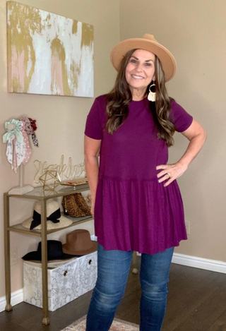 Kacie Ruffle Bottom Top in dark purple with jeans and tan hat